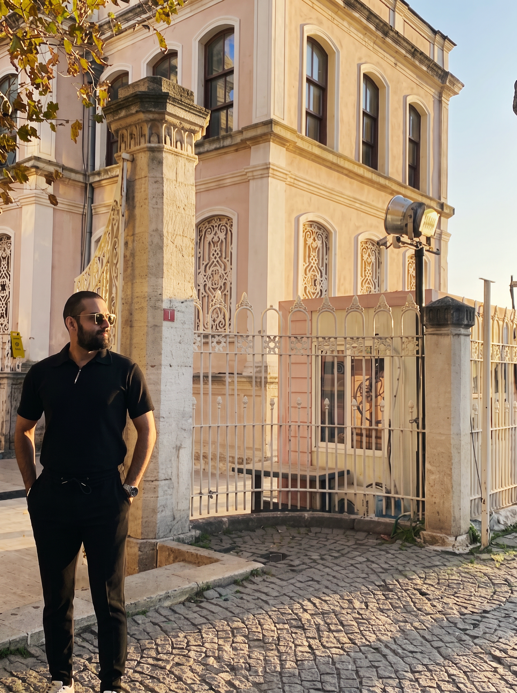 Sam, founder and perfumer of Alanoir, in black beside historic architecture
